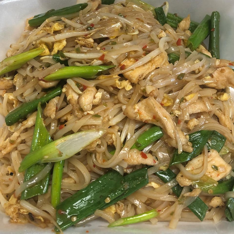 Close-up of The Asian Express's chicken Pad See Ew with wide noodles, green onions, and bean sprouts.